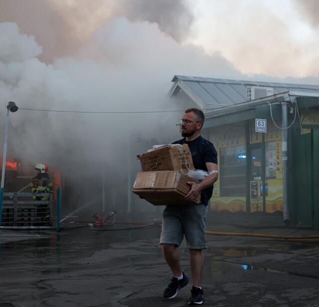 Un homme transporte des cartons contenant des objets récupérés sur le marché aux livres ravagé par un incendie